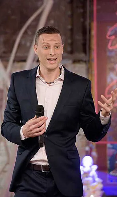 Dr. Noah De Koyer speaking to an audience, microphone in hand