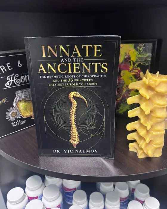 The book Innate and the Ancients on the office shelf beside a beeswax spine candle